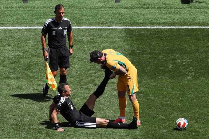 Trọng tài Felix Zwayer được cầu thủ Australia hỗ trợ căng cơ trong trận Mỹ thắng Australia 2-0